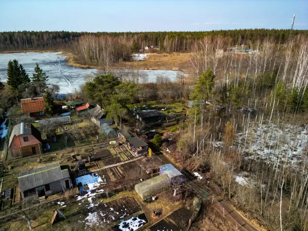 Вид с воздуха на дачный дом, теплицы и прилегающий лес на берегу озера в черте Даугавпилса